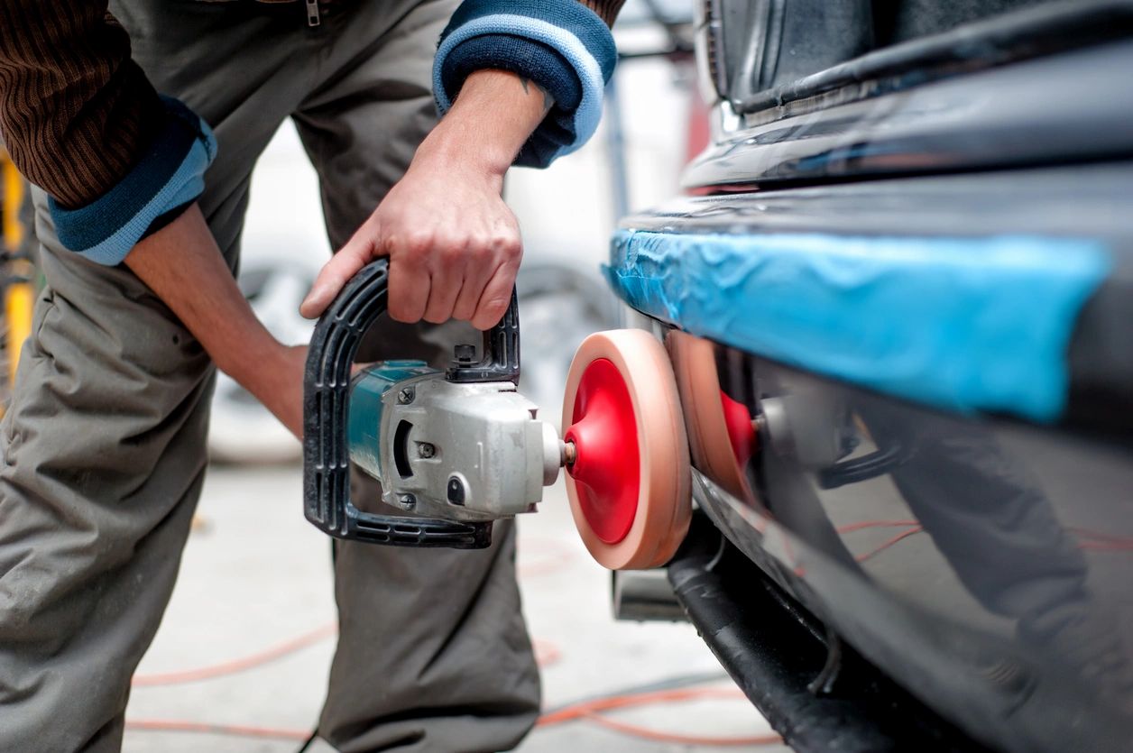 A person with a power tool is working on a car.