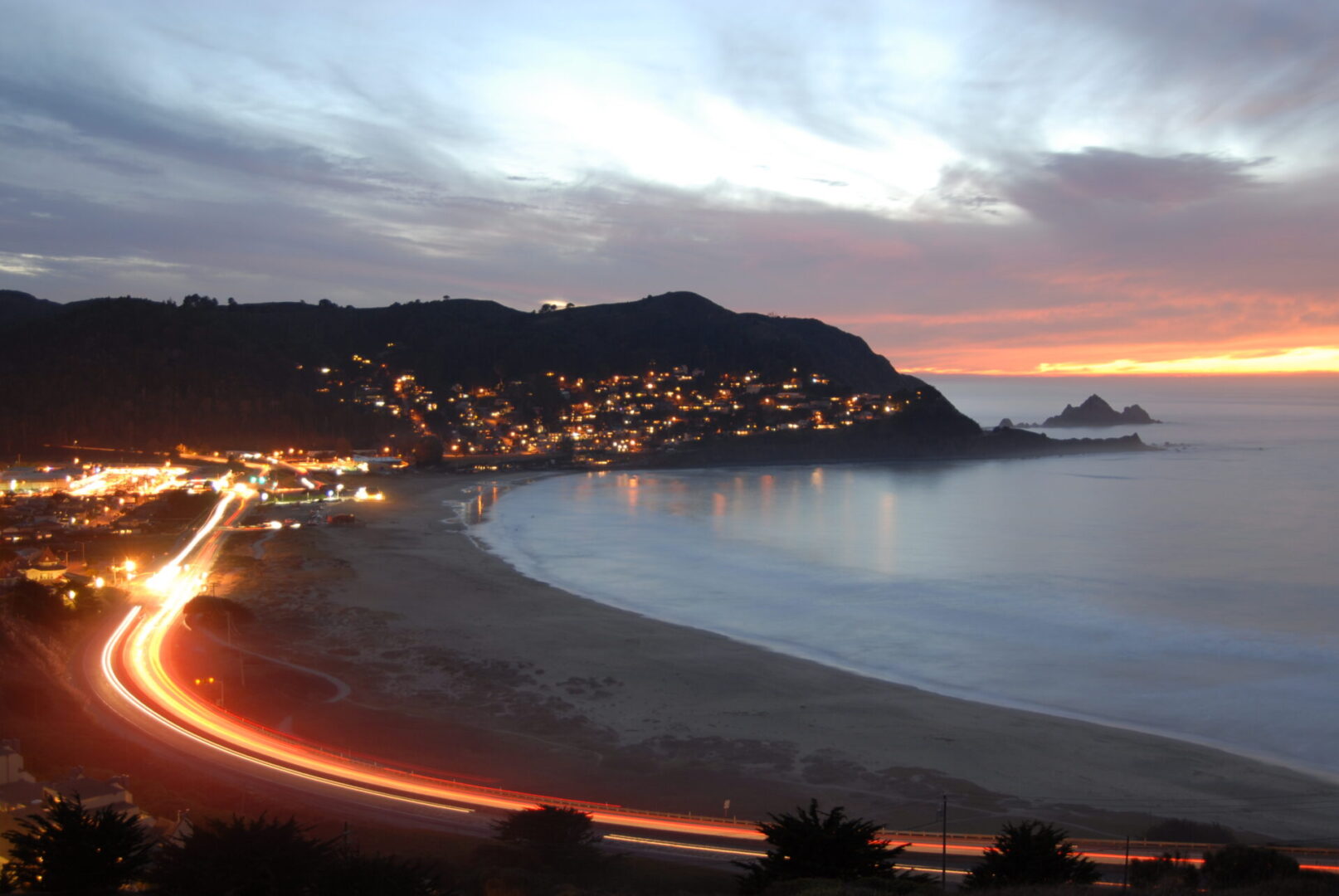 A view of the beach at night with lights on.